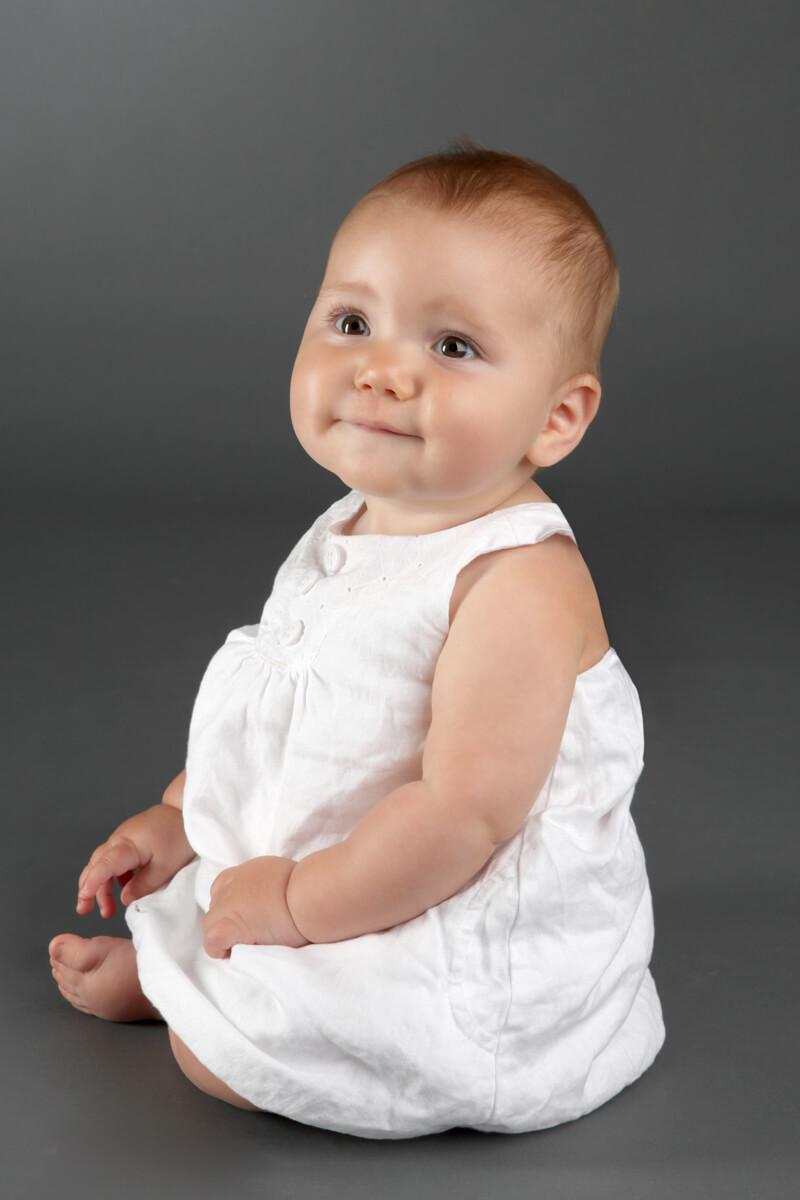 Baby poses for in-studio portrait with cute white dress