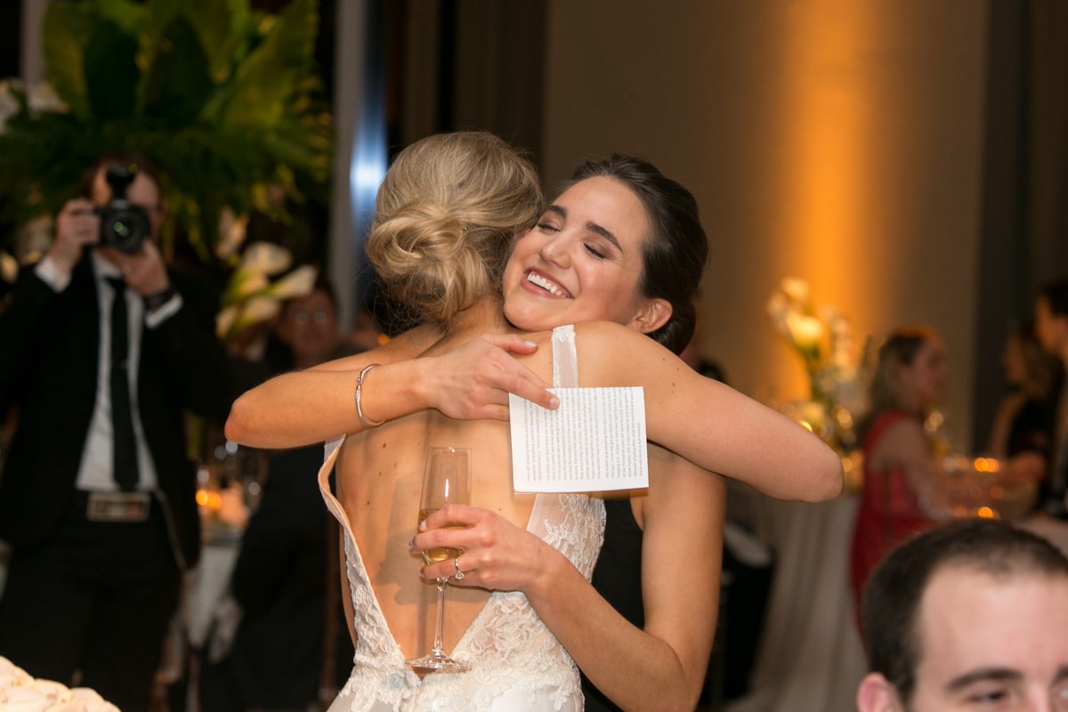 Bride hugs sister after wedding toast.